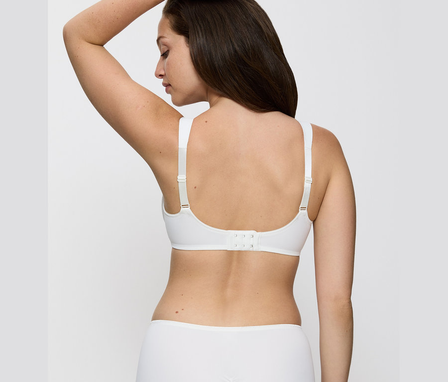 Rückansicht einer Frau mit braunen Haaren, die einen vanillefarbenen Triumph Essential »Minimizer W X« BH trägt.
