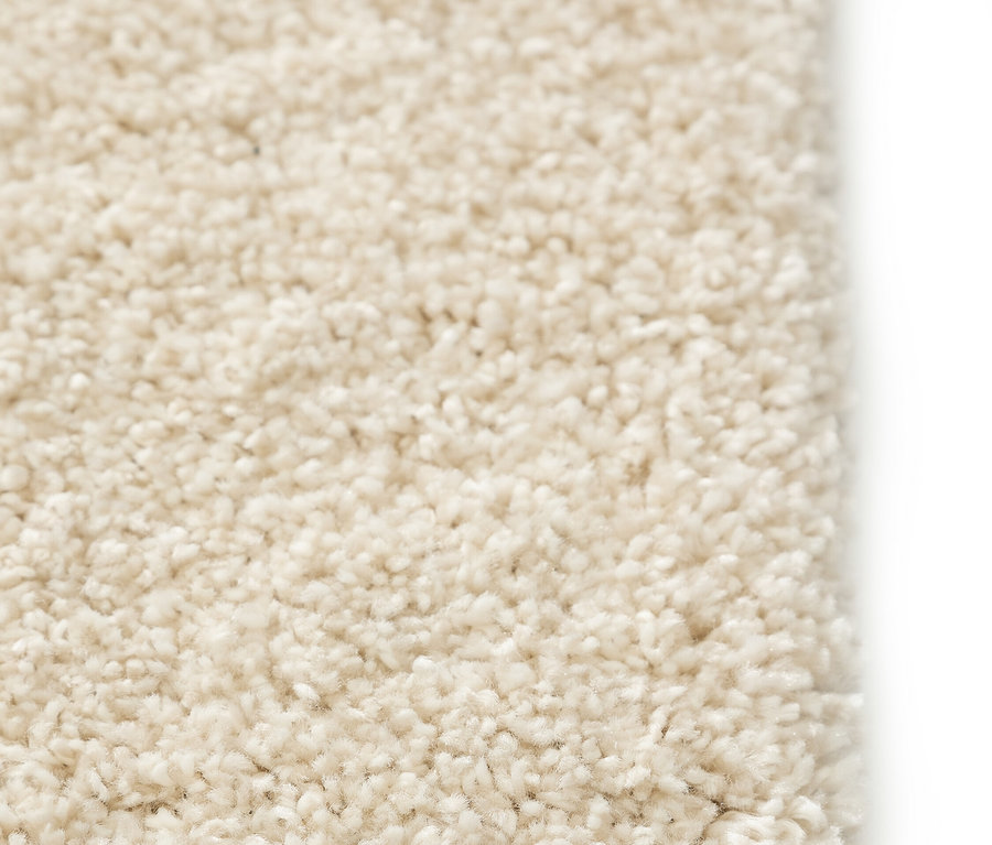 Nahaufnahme einer Ecke eines cremefarbenen Teppichs mit hohem Flor.