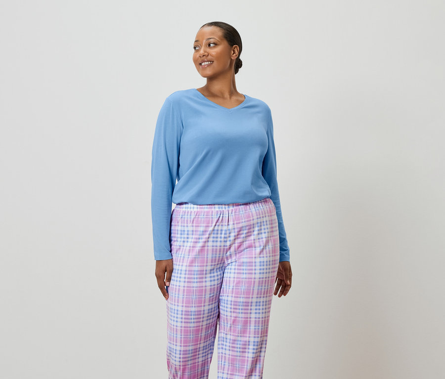 Frau trägt einen hellblauen Pullover und eine karierte Pyjamahose.