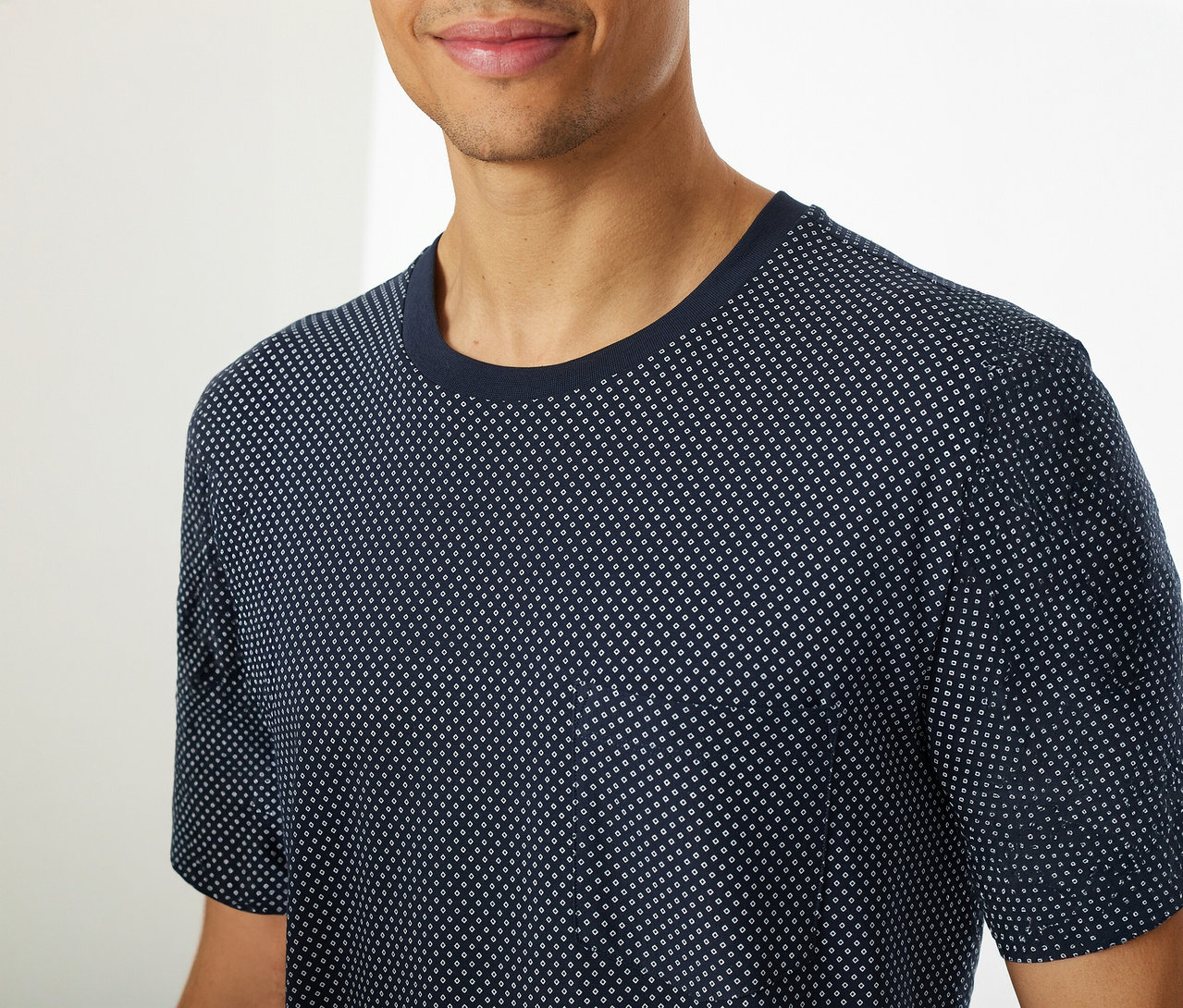 Mann trägt ein SCHIESSER Shorty-Pyjama-Set mit blauem, kurzärmeligem Oberteil mit Punktmuster.