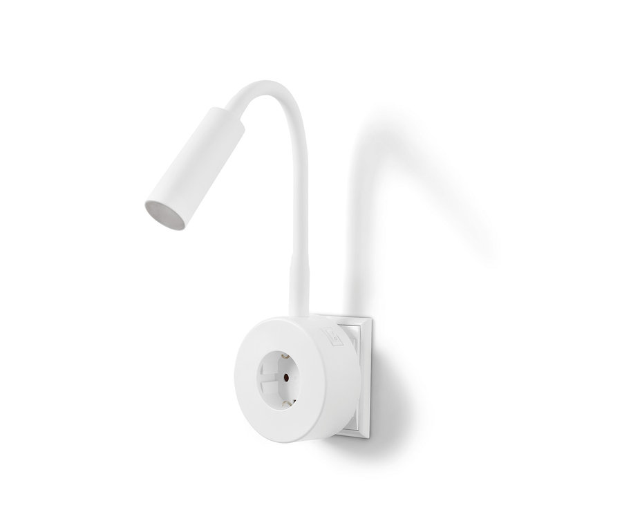 Eine weiße LED-Schwenkleuchte ist an einer weißen Steckdose an einer weißen Wand befestigt.
