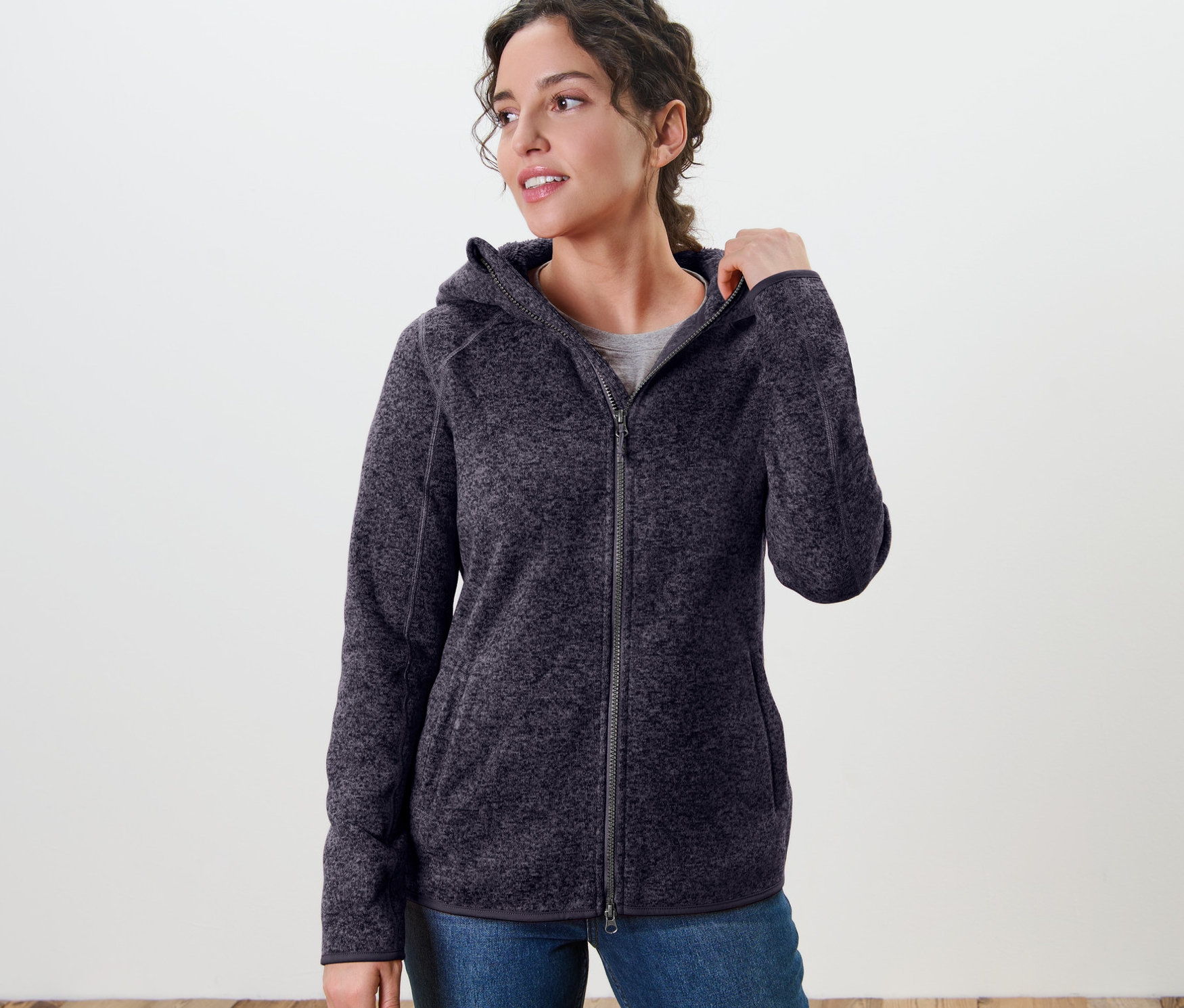 Frau trägt eine Kapuzen-Strickfleecejacke, dunkelblau meliert.