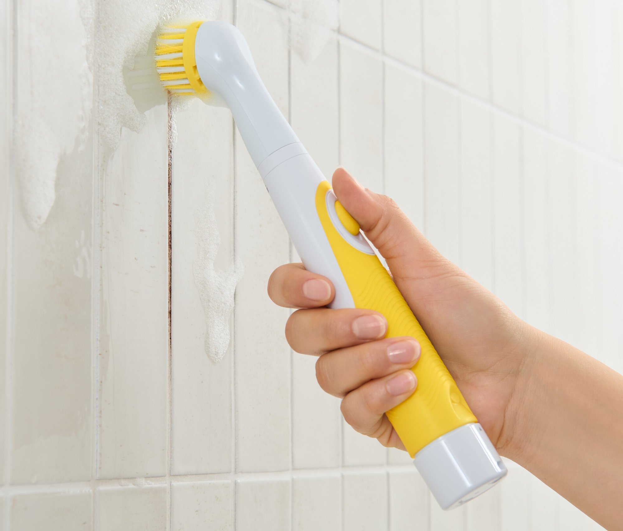 Eine Hand benutzt eine elektrische Reinigungsbürste, um schmutzige Fliesen zu reinigen.