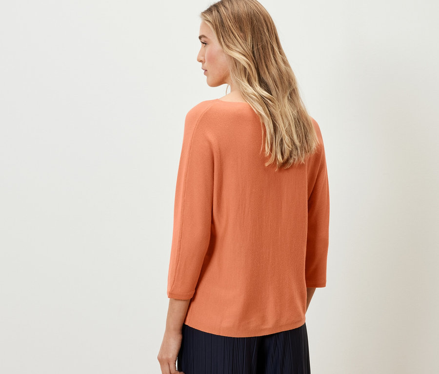 Frau von hinten trägt einen peachfarbenen Merino-Feinstrickpullover.