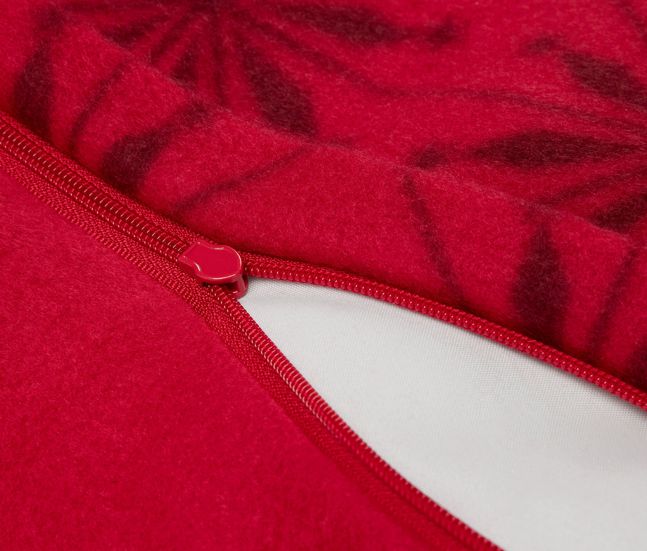 Detailaufnahme eines roten Kissenbezugs mit Reißverschluss und dunklem Blumenmuster.