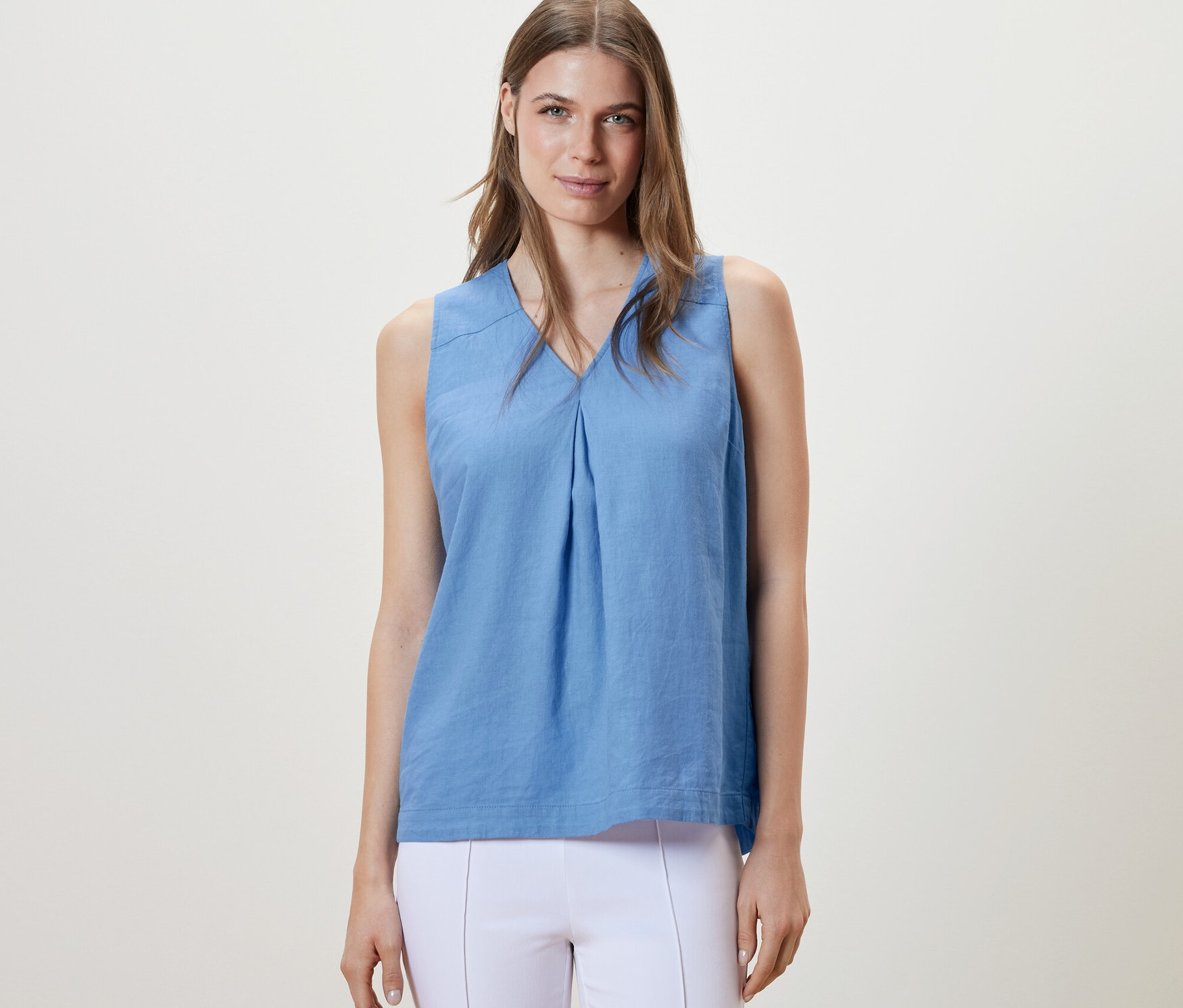 Frau trägt eine hellblaue, ärmellose Leinenbluse.