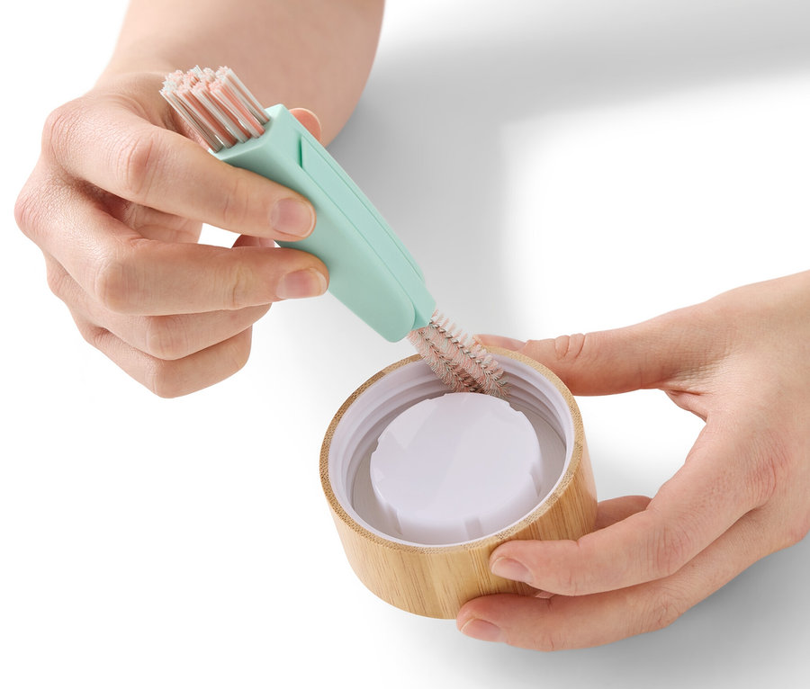 Eine Frau reinigt einen Flaschendeckel mit einer 3-in-1-Reinigungsbürste.