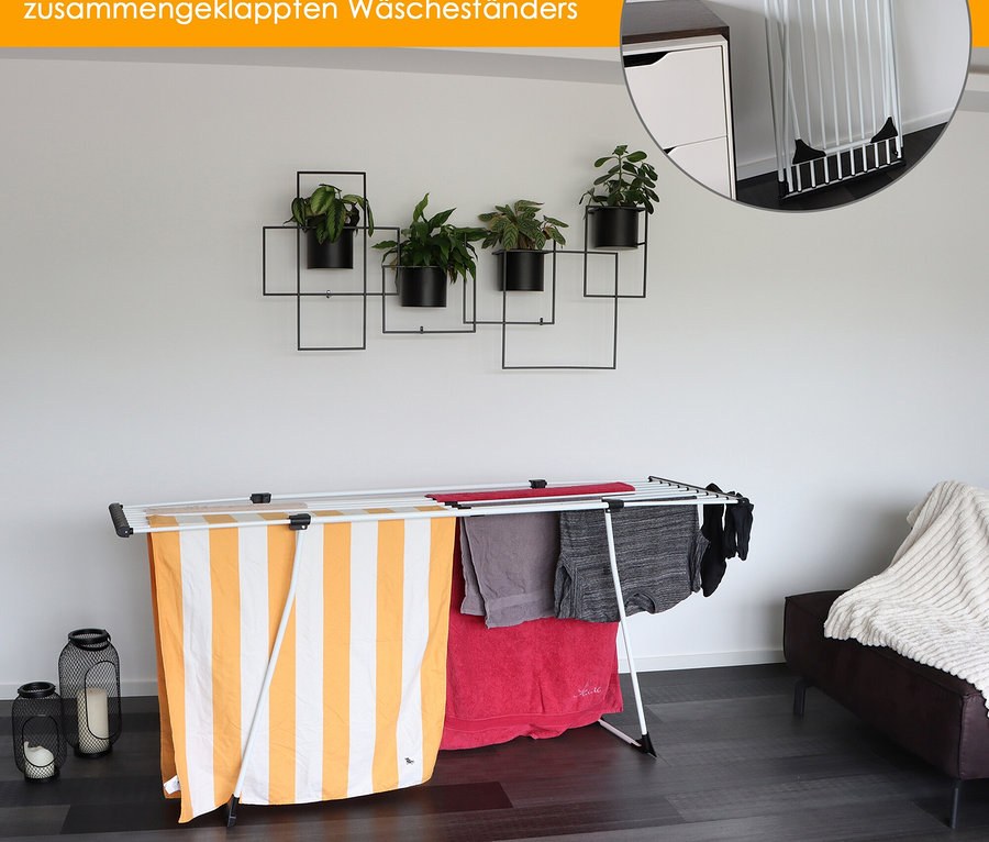 Auf weißem Hintergrund steht ein weißer Yoursol Teleskop-Wäscheständer mit gelb-weiß gestreiften Handtüchern und grauer Kleidung.