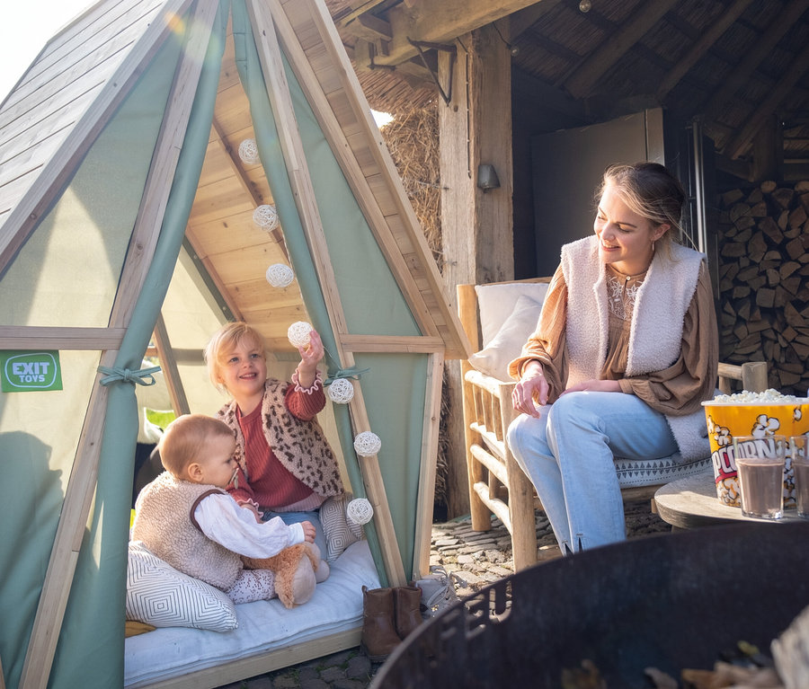 Kinder spielen im EXIT Spielhaus Yuki 100, während eine Frau daneben sitzt.