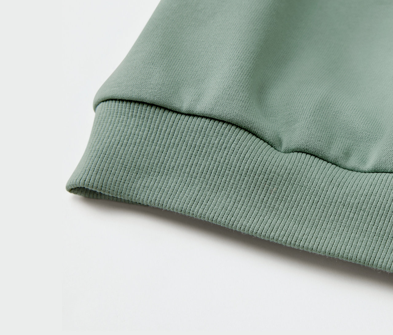 Detailansicht eines grünen Kinder-Sweatshirts mit geripptem Bündchen.