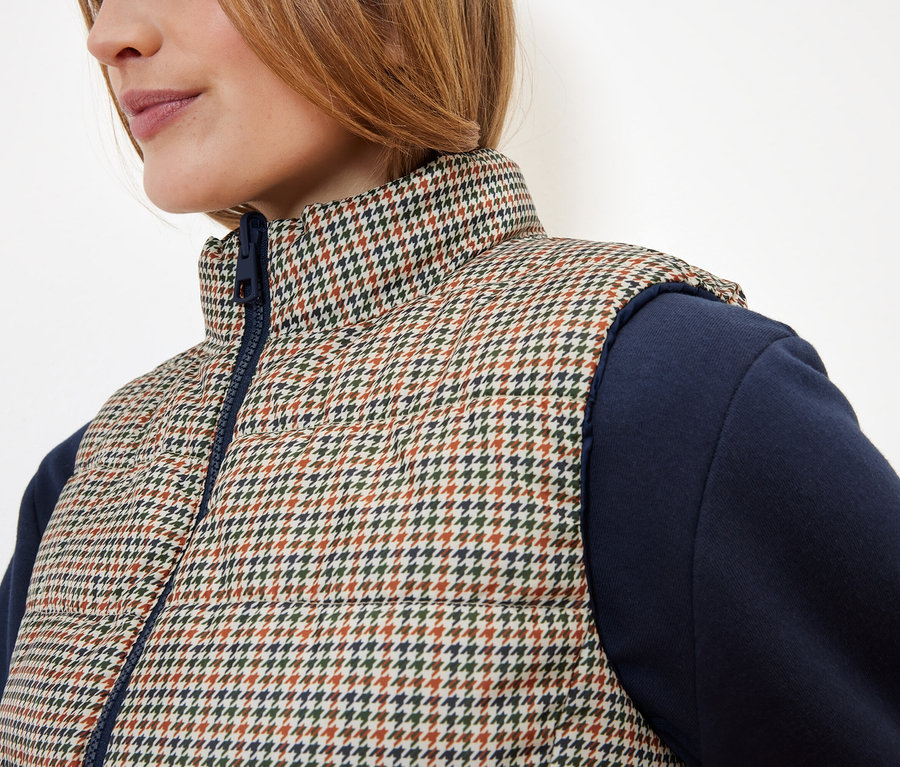 Detail einer Damen Steppweste mit Hahnentrittmuster und blauen Ärmeln.