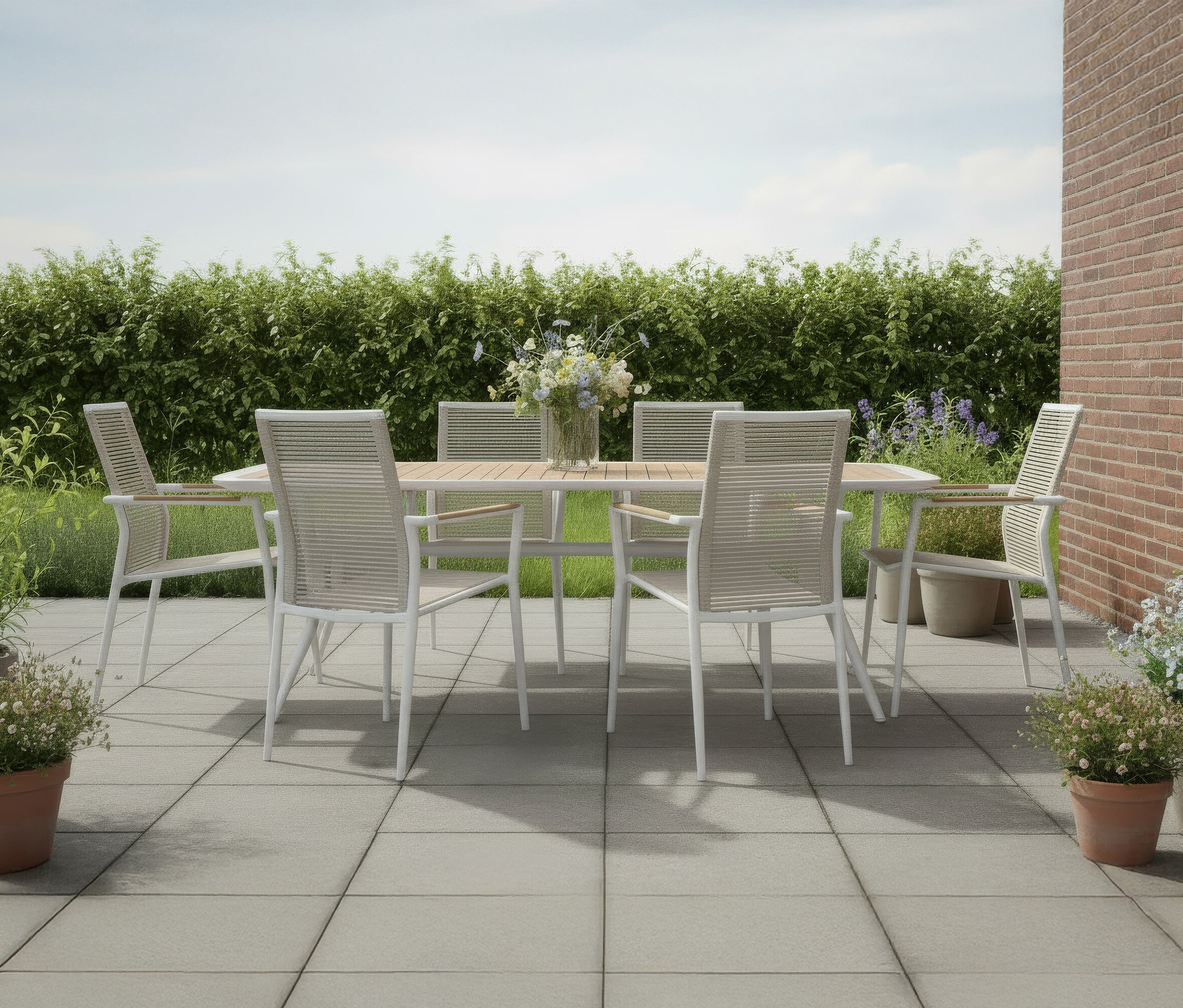 Auf einer Terrasse steht ein DeVries Dining-Set mit einem Tisch (220 x 100cm) und Stapelstühlen (2er-Set).