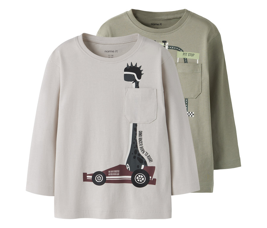 Zwei NAME IT Langarmshirts, eines beige mit Dinosaurier-Rennfahrer-Motiv und Tasche, das andere olivgrün mit Rennstrecken-Motiv und Tasche.