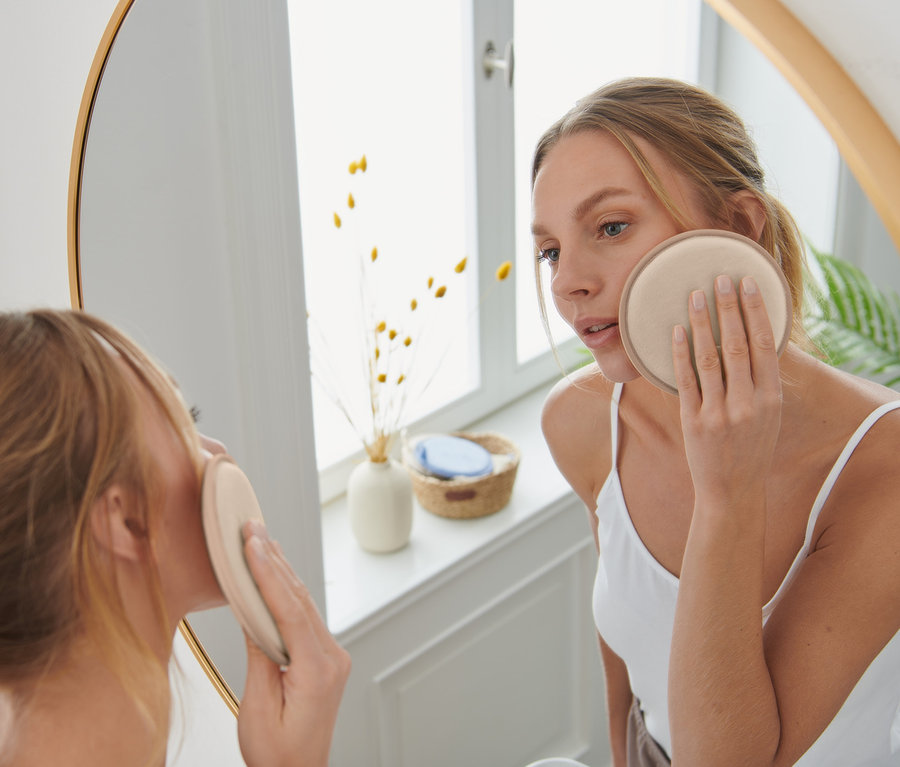 Frau entfernt Make-up mit einem braunen, wiederverwendbaren XL-Abschminkpad.