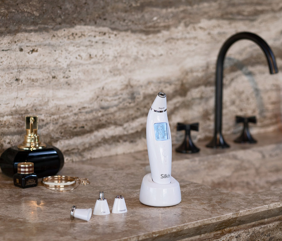 Auf einer Marmorplatte stehen ein Silk’n-Mikrodermabrasionsgerät »ReVit Prestige« und Zubehör.