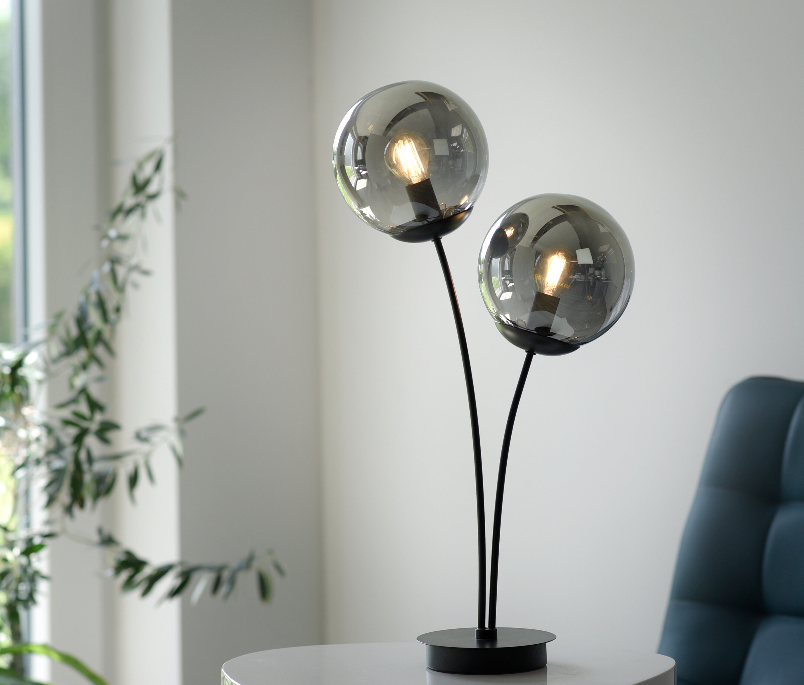 Schwarze JUST LIGHT Tischleuchte »Big Widow« mit zwei Glaskugeln steht auf einem weißen Tisch.