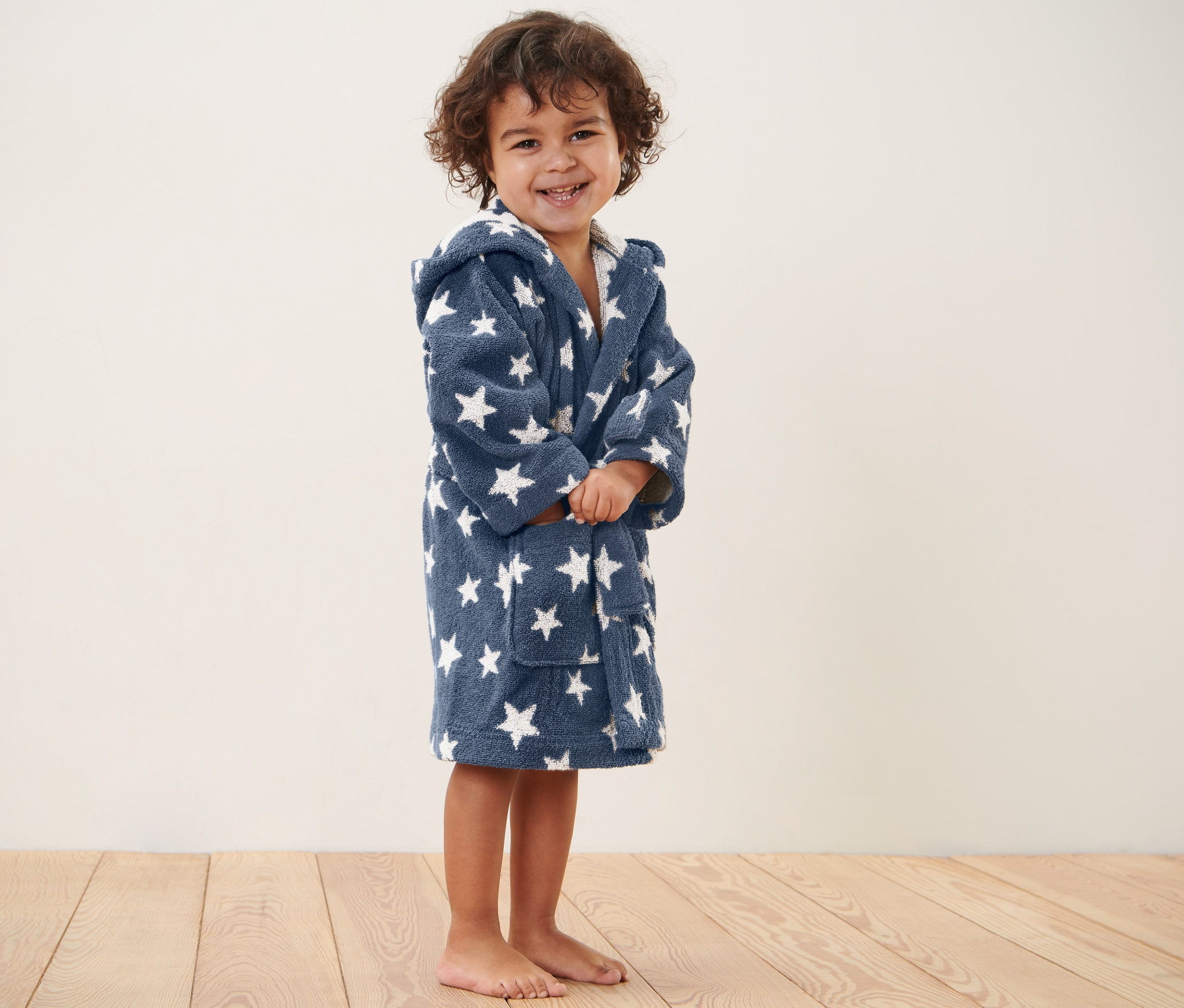 Ein Kind steht und trägt einen Kinder-Bademantel.