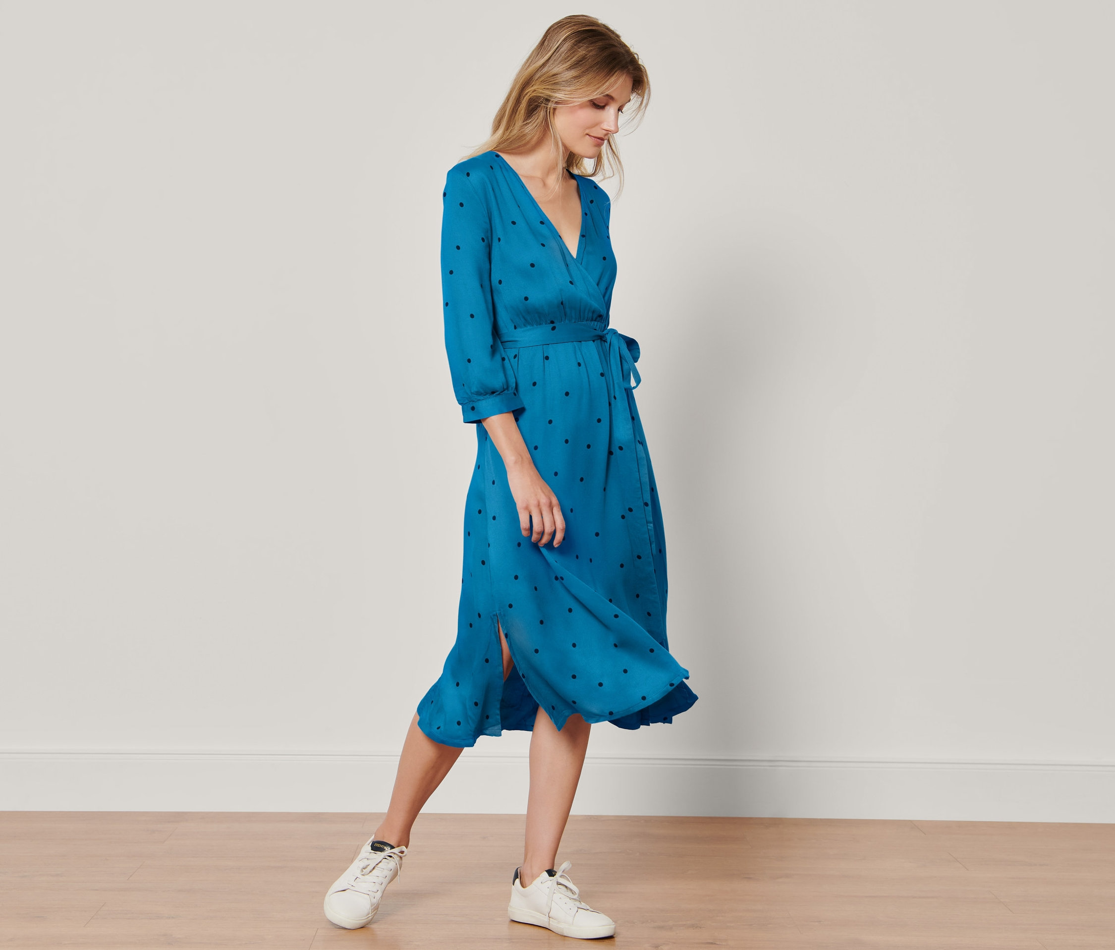 Frau steht und trägt ein gepunktetes Webkleid.