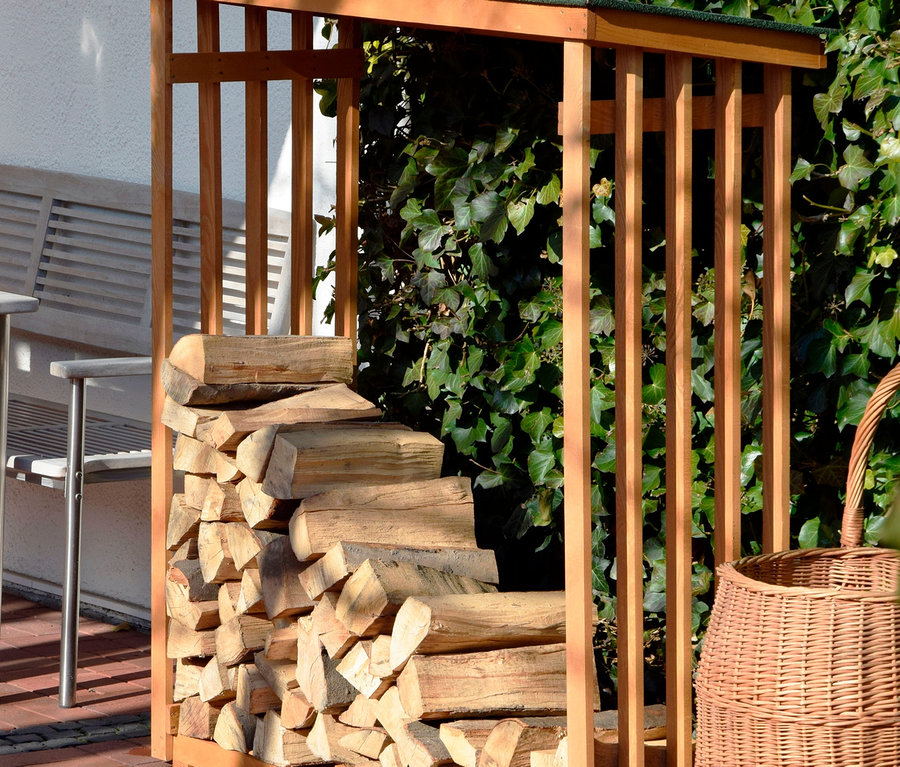 Ein Kaminholz-Regal, 15 mm, Kiefer, teilweise mit Holz gefüllt, steht auf einer Ziegelterrasse.