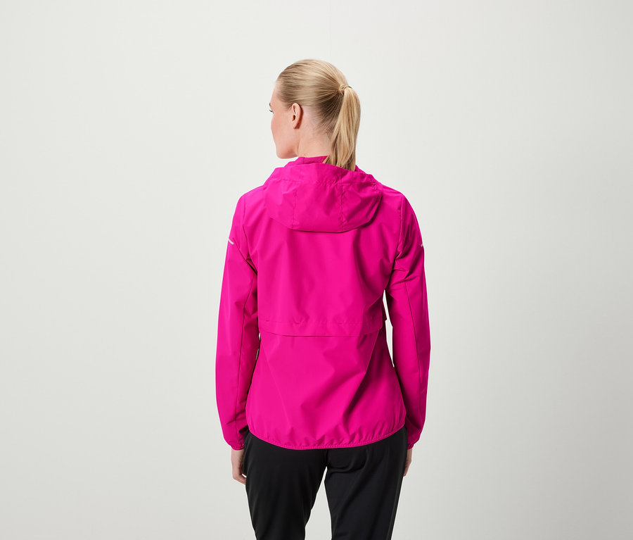 Rückansicht einer Frau mit blonden, zum Pferdeschwanz gebundenen Haaren, die eine pinkfarbene Jacke mit Kapuze und eine schwarze Hose trägt.