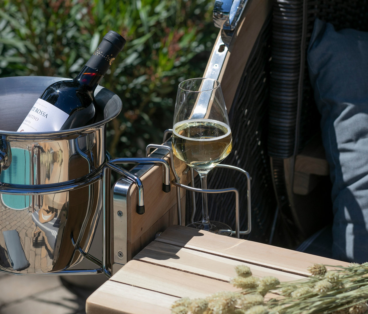 Rotweinflasche in einem Eiseimer neben einem Glas Weißwein auf einem Holztisch.