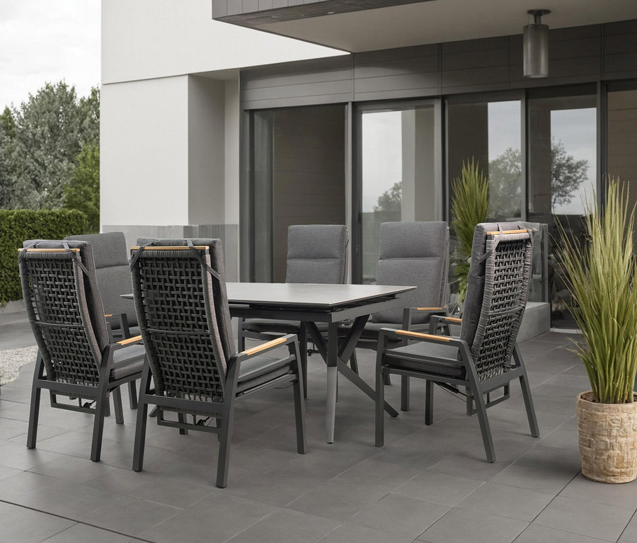 Sechs graue Stühle mit Armlehnen stehen um einen grauen Tisch auf einer Terrasse.