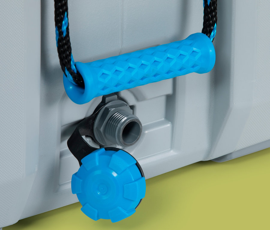 Detailaufnahme einer grauen Lifetime-Premium-Kühlbox mit blauem Griff und Ablassventil vor gelbem Hintergrund.