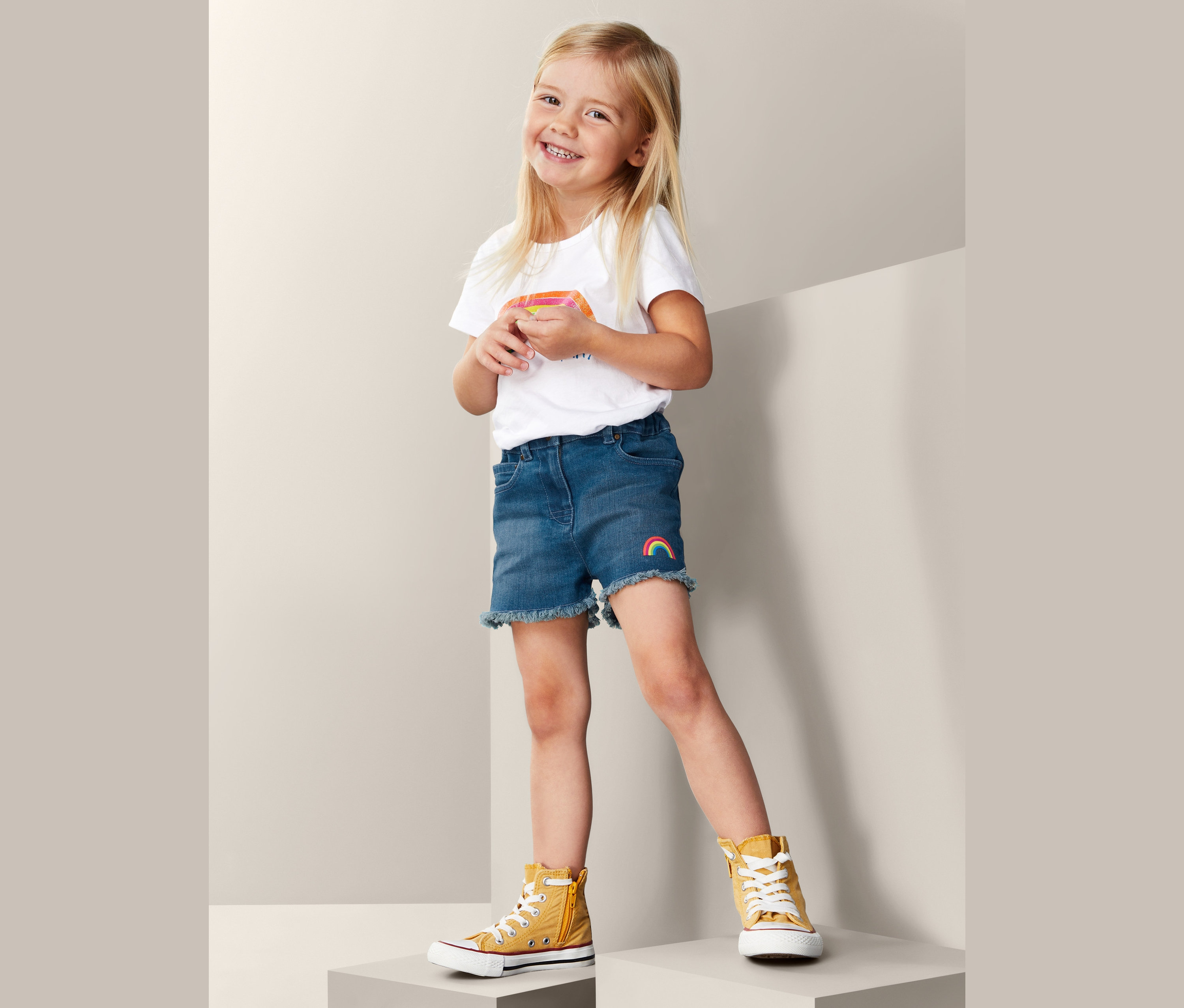 Lächelndes Mädchen trägt Denim-Shorts und T-Shirt.