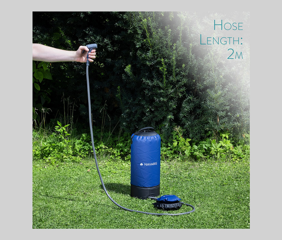 Hand hält Duschkopf der Navaris Campingdusche mit Fußpumpe auf Gras.