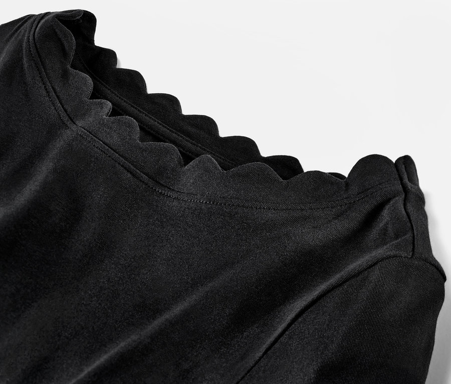 Detailaufnahme eines schwarzen Shirts mit 3/4-Arm und gewelltem Ausschnitt.