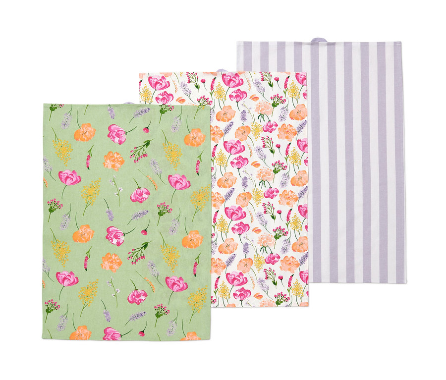 Drei Geschirrtücher: ein grünes mit Blumenmuster, ein geblümtes und ein weißes mit lila Streifen.