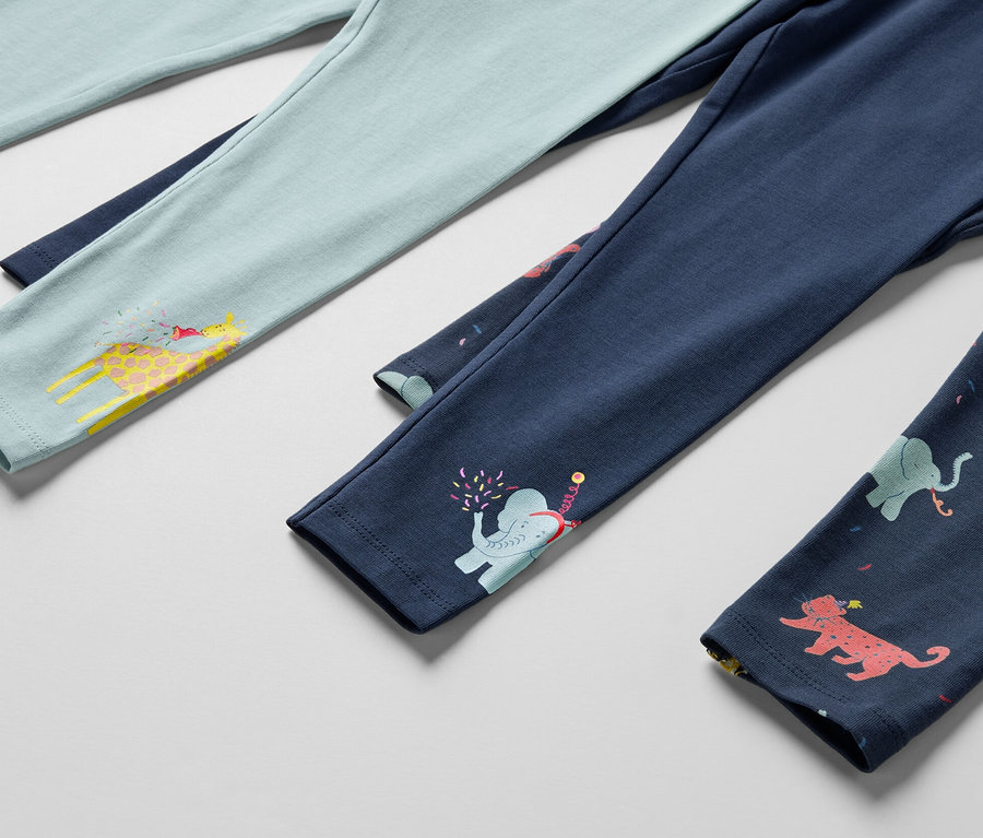 Detail von drei Kinderleggings, eine hellblau mit Giraffe, eine dunkelblau mit Elefant und eine dunkelblau mit Tieren.
