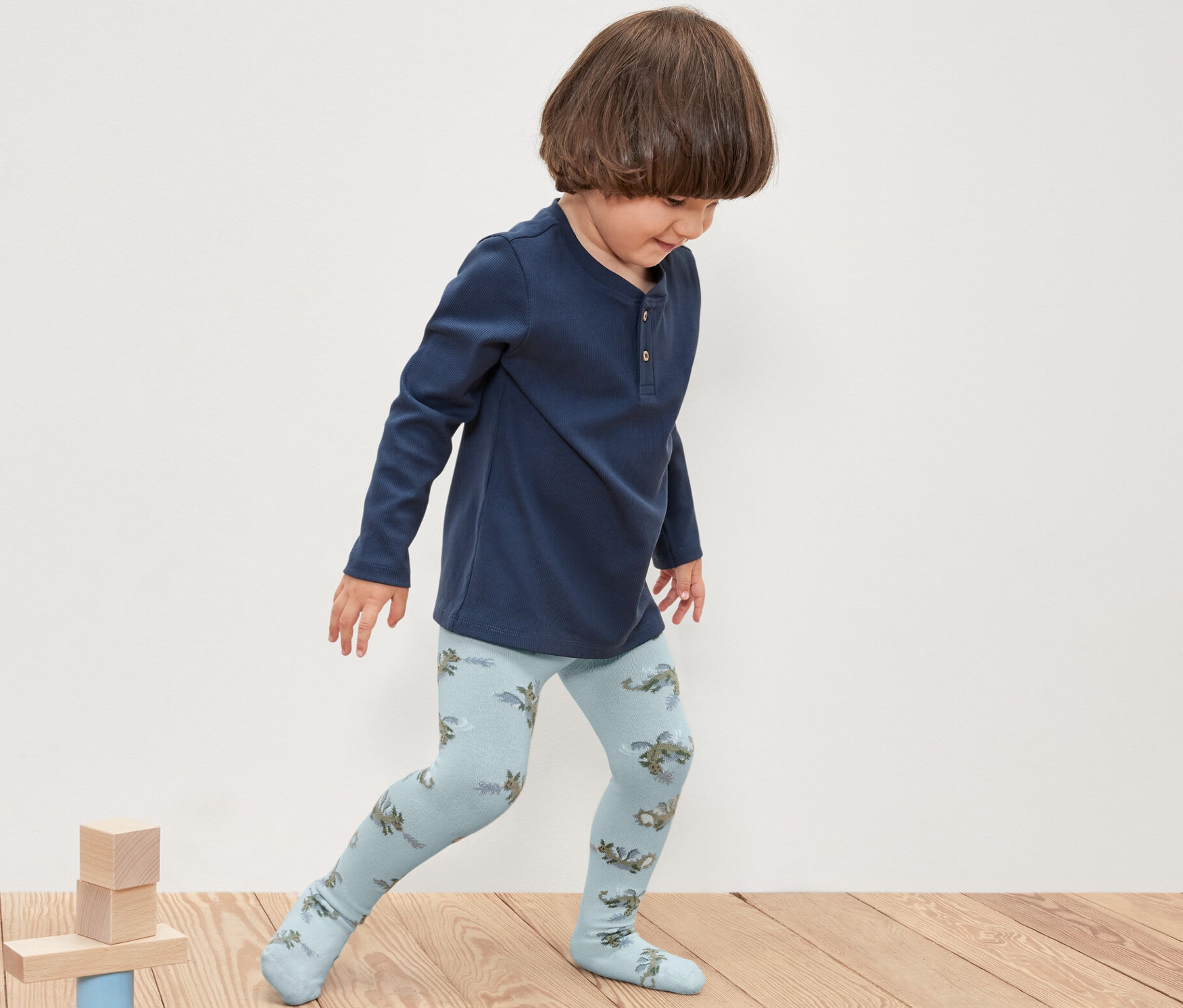 Ein Junge spielt mit Holzklötzen und trägt 5 Kinder-Strumpfhosen, Ritter.