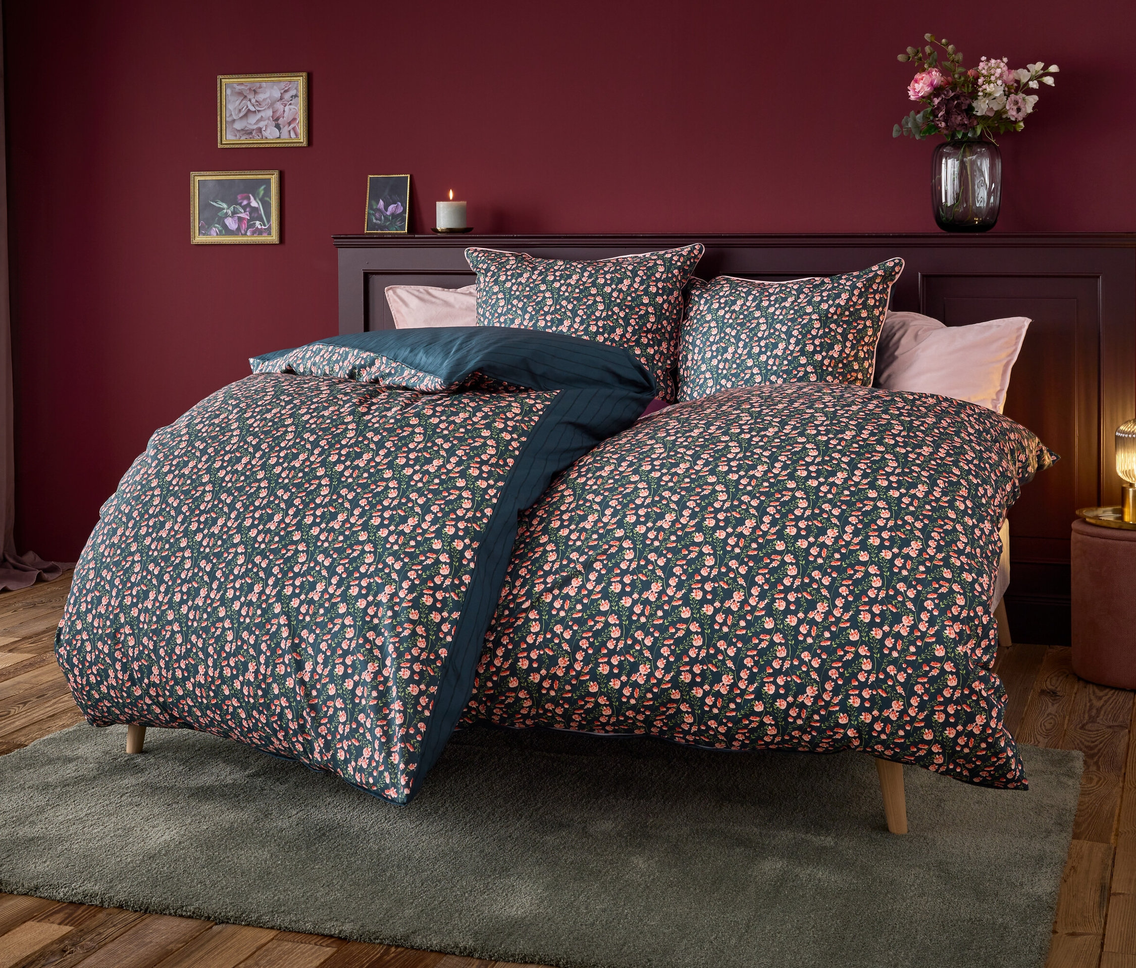 Bett mit marineblauer Bettwäsche mit Blumenmuster.