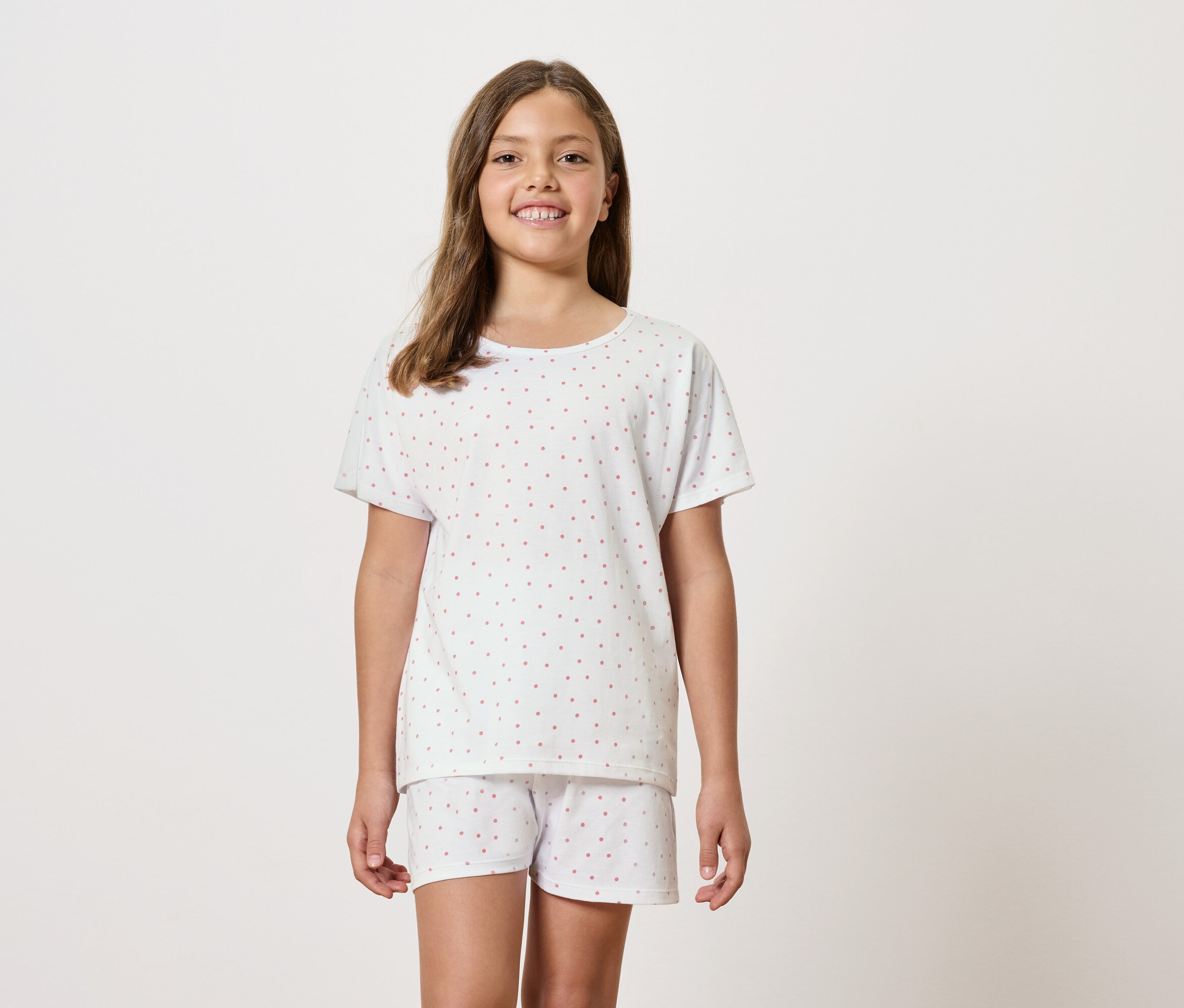 Mädchen trägt weißen kurzärmeligen Schlafanzug mit Shorts.