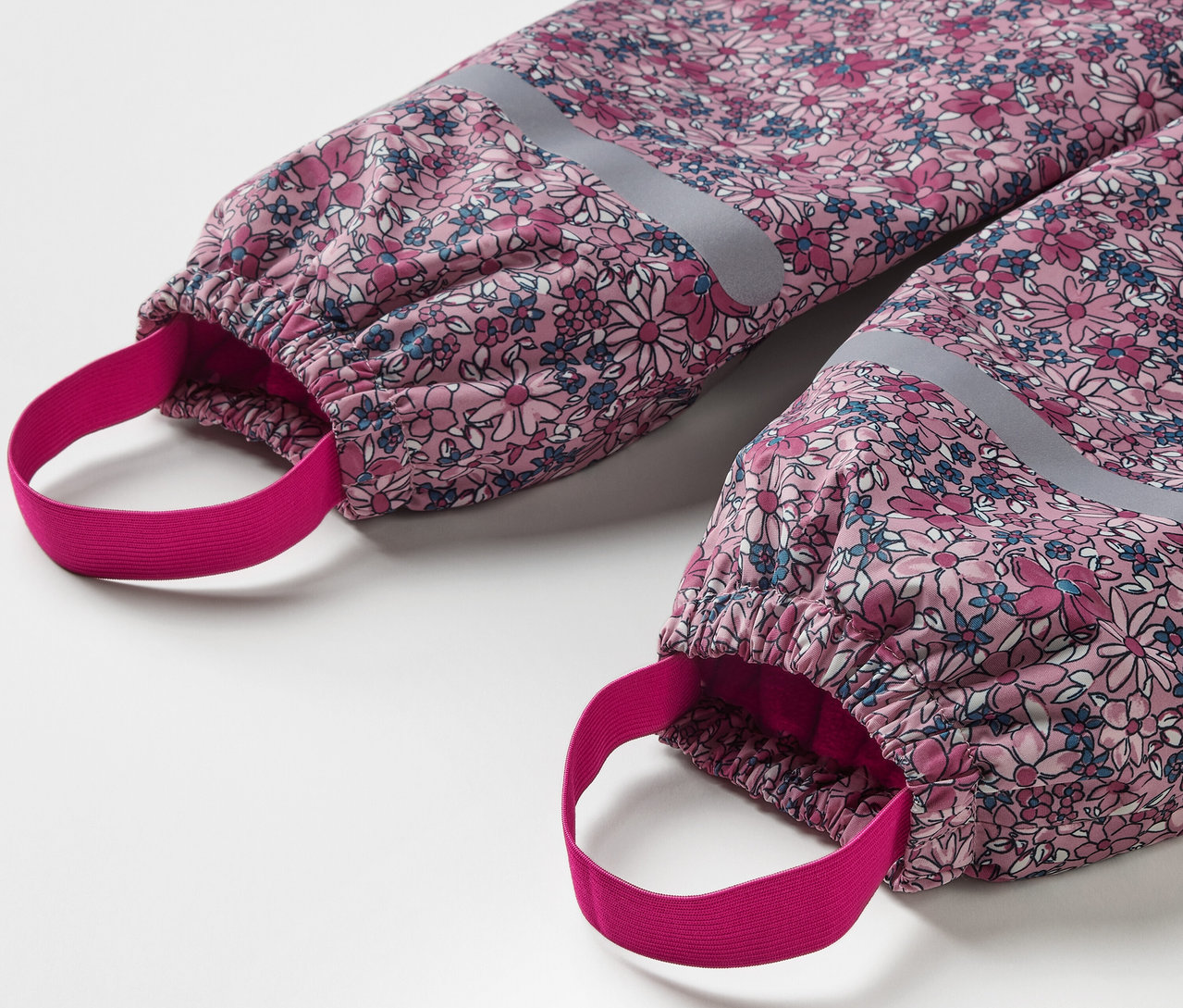 Detail einer Kinder-Thermo-Regenhose mit Blumenmuster und reflektierenden Elementen.