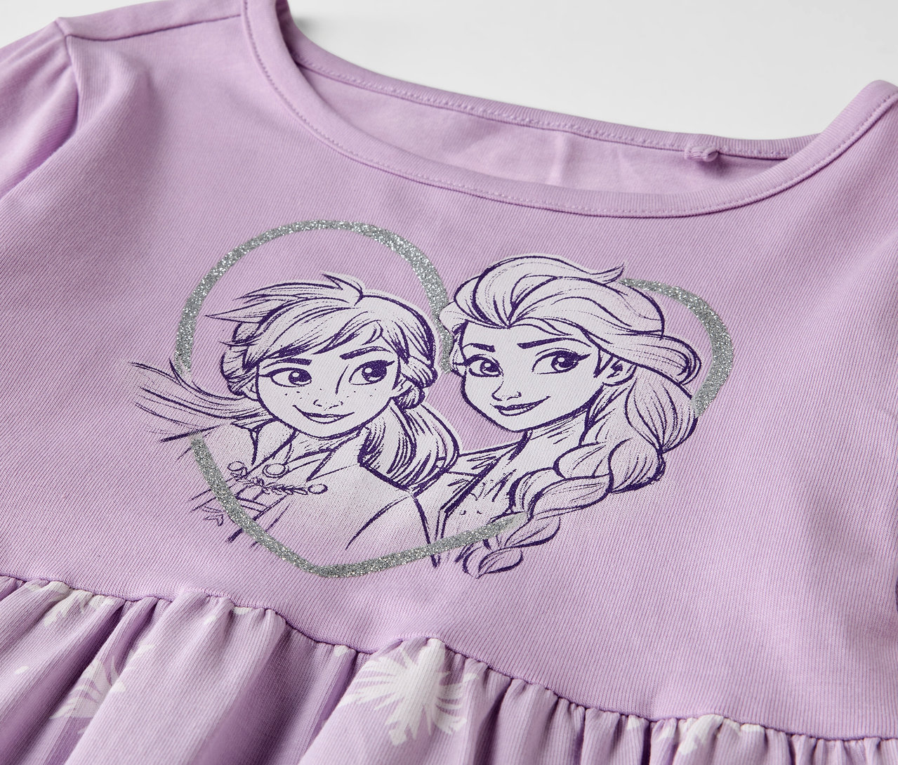 Nahaufnahme eines lila Kinder-Jerseykleids »Eisprinzessin« mit Anna- und Elsa-Motiv.
