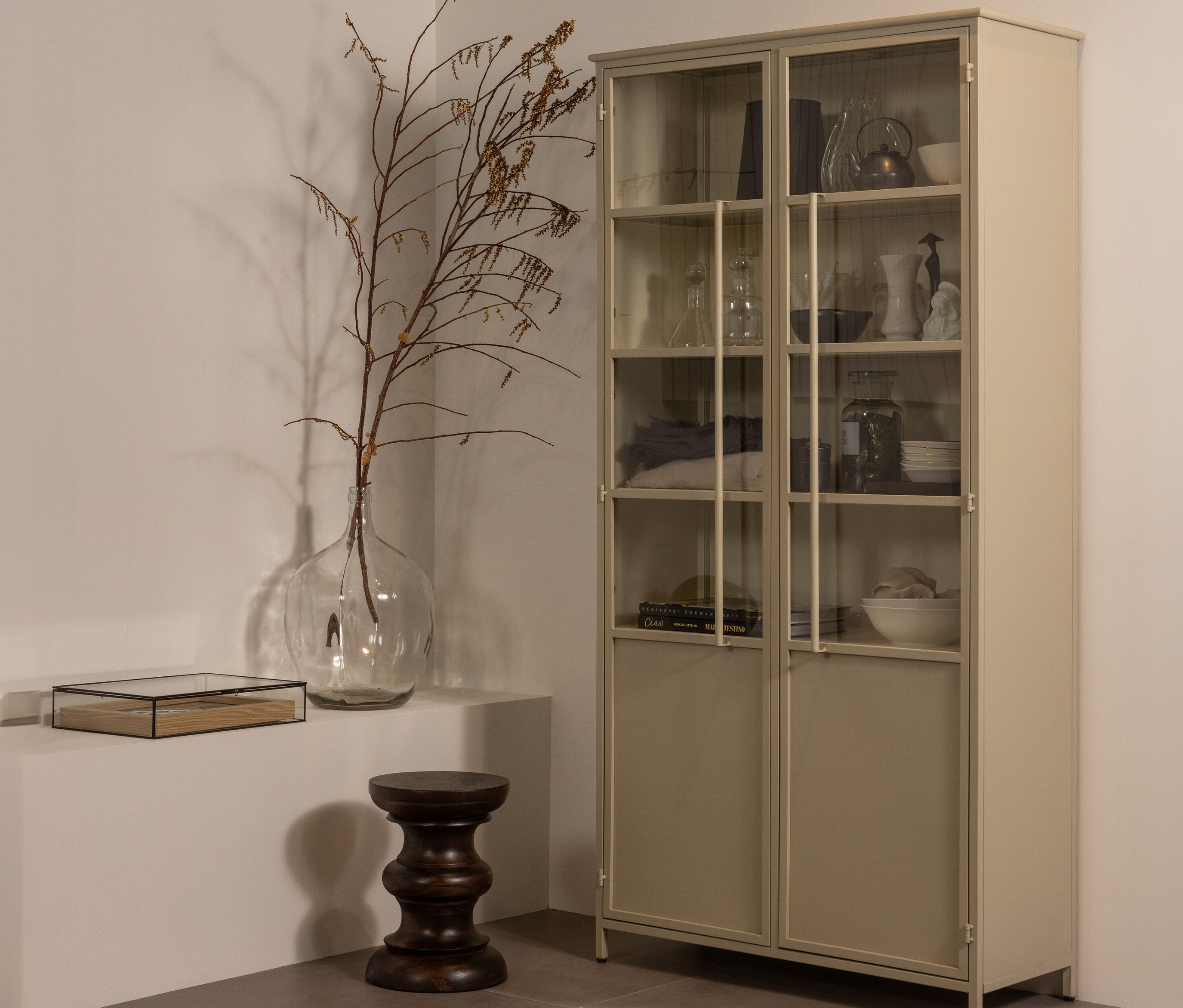 Eine BePureHome »Exhibit« Metall-Vitrine in Khaki steht im Raum.