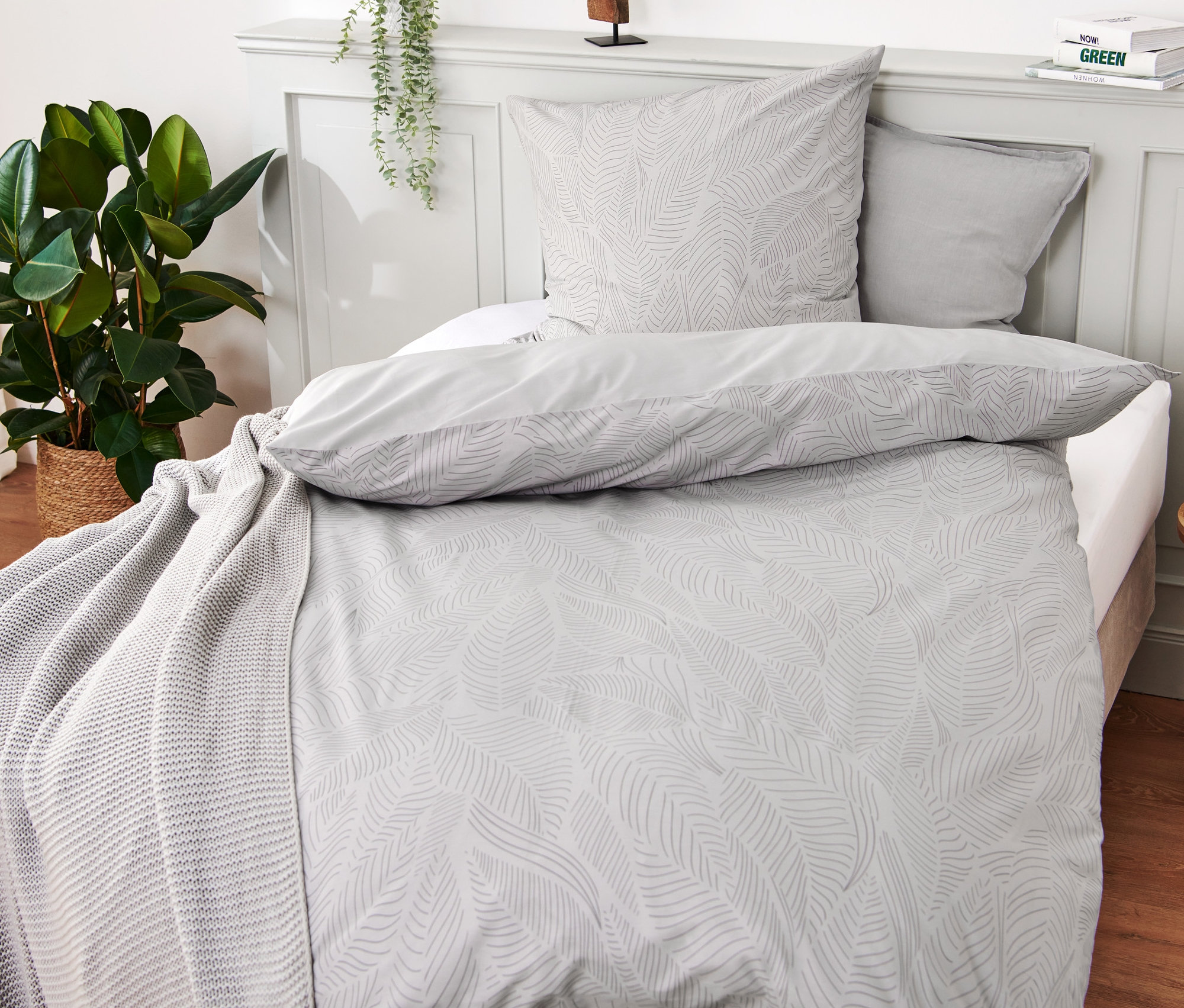 Graue Premium-Baumwoll-Bettwäsche in Normal- und Übergröße mit Blattmuster auf einem Bett.