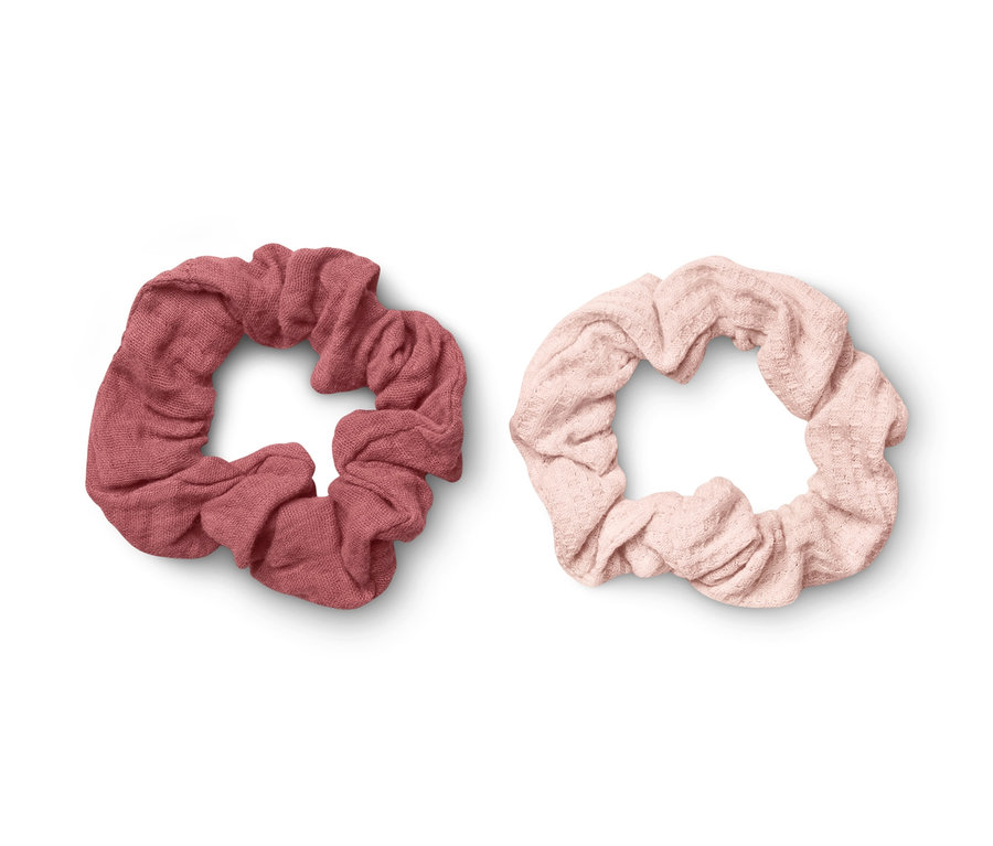 Zwei Haargummis liegen auf einem weißen Hintergrund. Eines ist rosa, das andere rot.