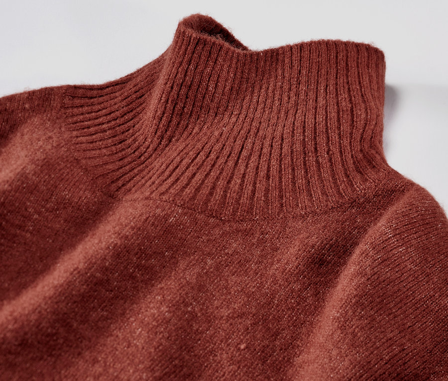 Detailansicht eines braunen Strickkleids mit Wollanteil und Rollkragen.