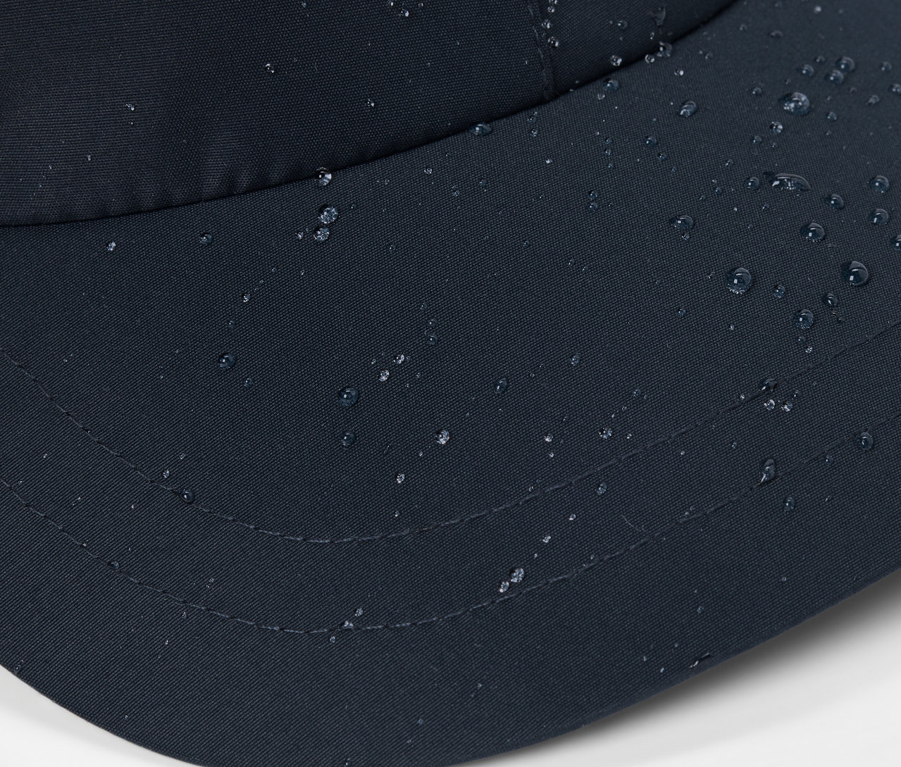 Nahaufnahme einer schwarzen Allwetter-Kappe mit Wassertropfen auf der Oberfläche.