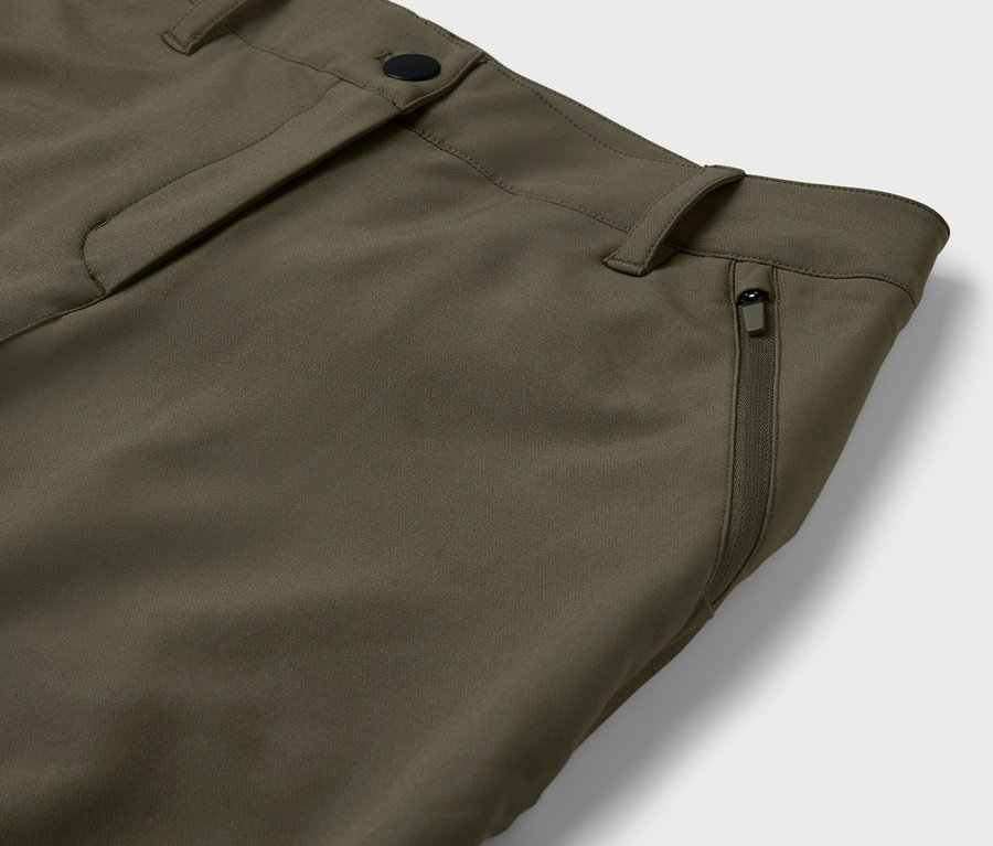 Detail einer olivgrünen Hose mit Reißverschlusstasche.
