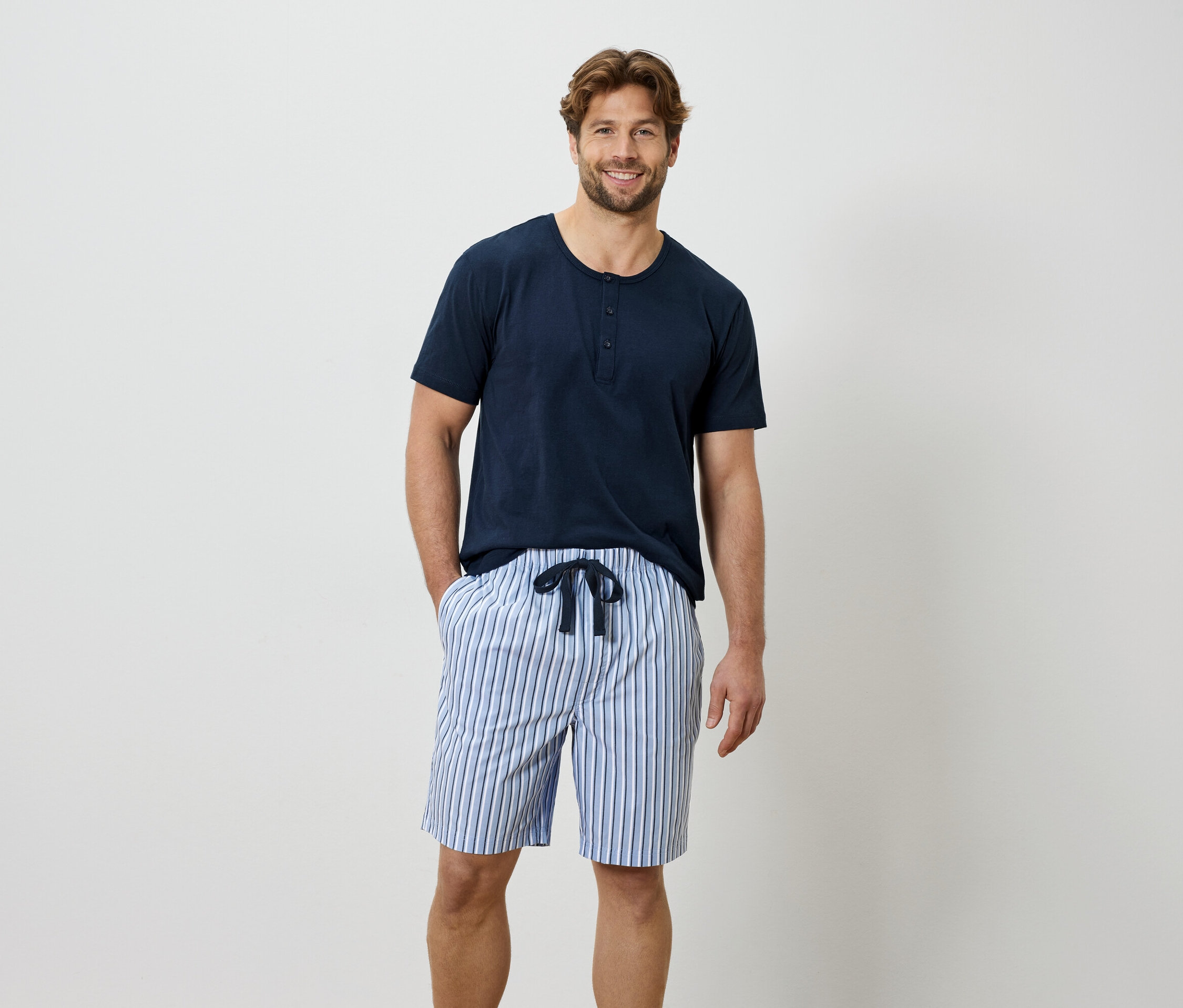 Mann mit blauem T-Shirt und gestreifter kurzer Hose.