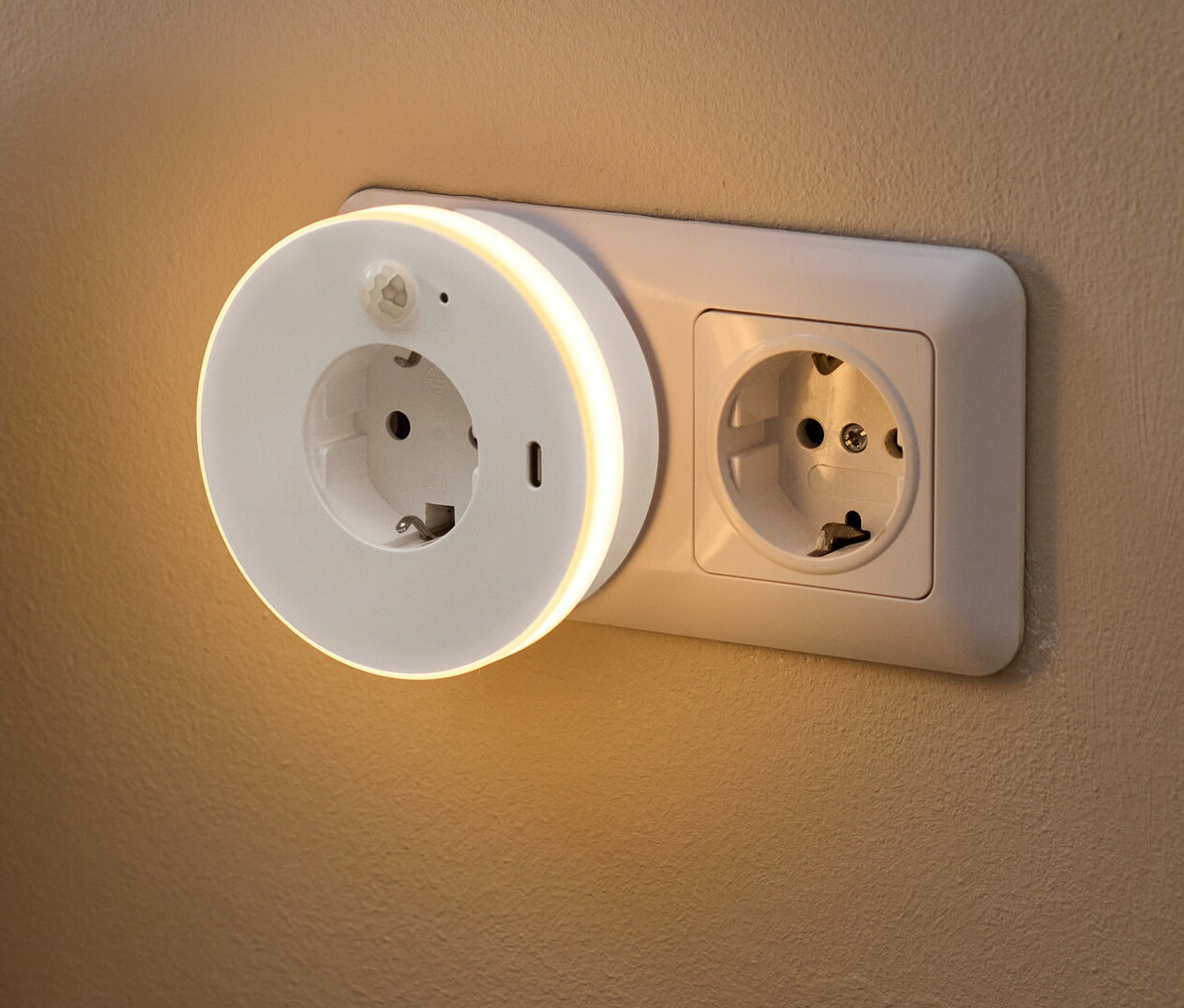 Ein LED-Nachtlicht mit Steckdose und USB-C-Buchse ist an der Wand eingesteckt.