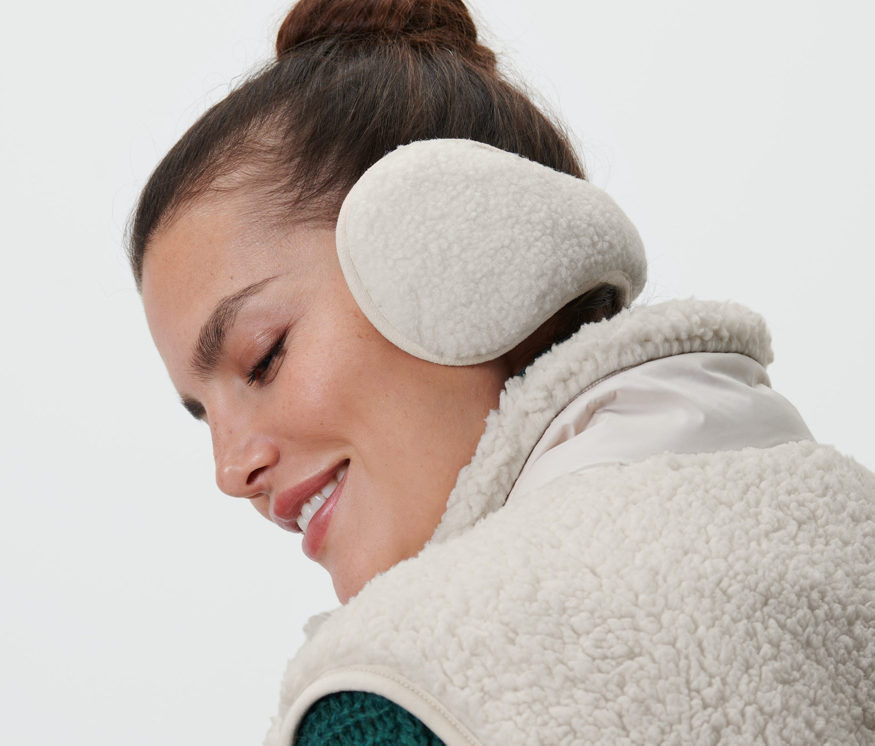 Frau mit braunen Haaren trägt Ohrenschützer.