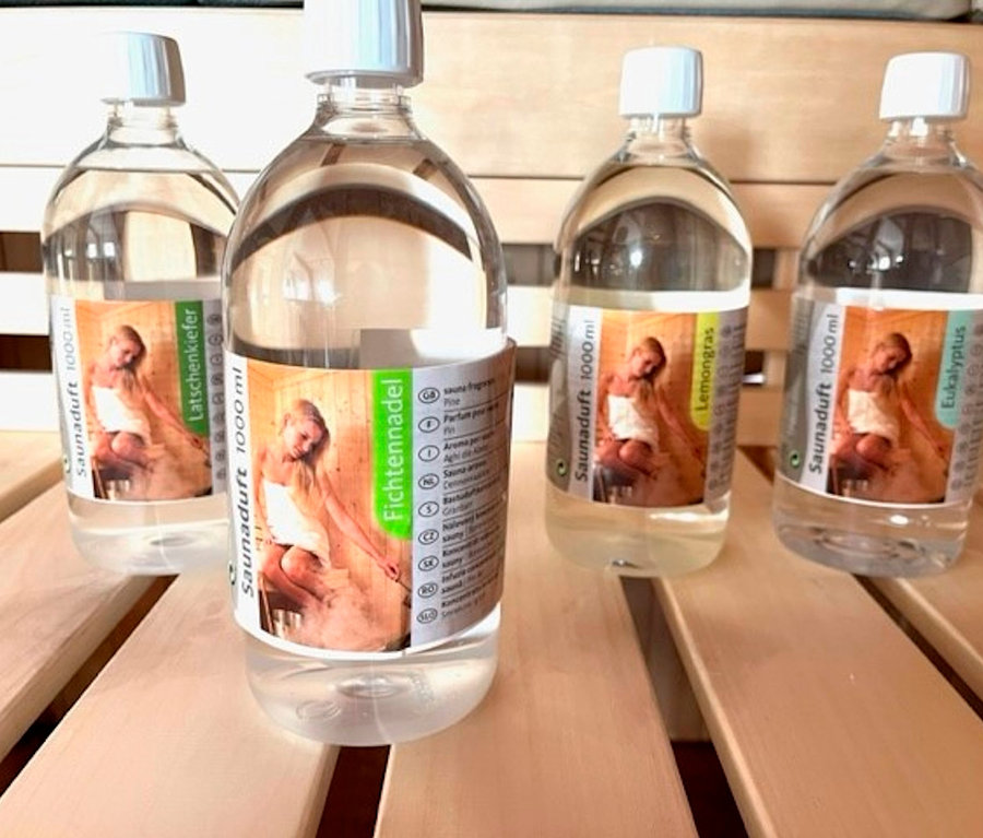 Vier Flaschen Karibu Sauna-Aufgusskonzentrat, je 1.000 ml, stehen auf einer Holzfläche.