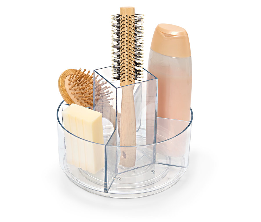 Ein durchsichtiger, drehbarer Behälter mit Seife, Haarbürste und einer Flasche Shampoo.