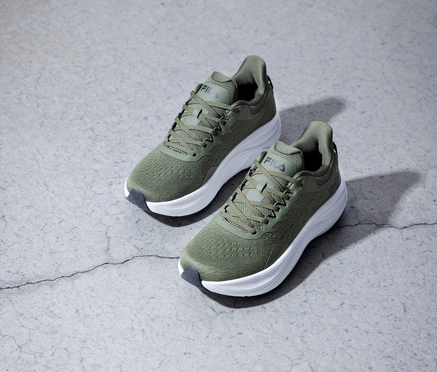 Zwei olivgrüne Fila Laufschuhe stehen auf einem grauen Untergrund.