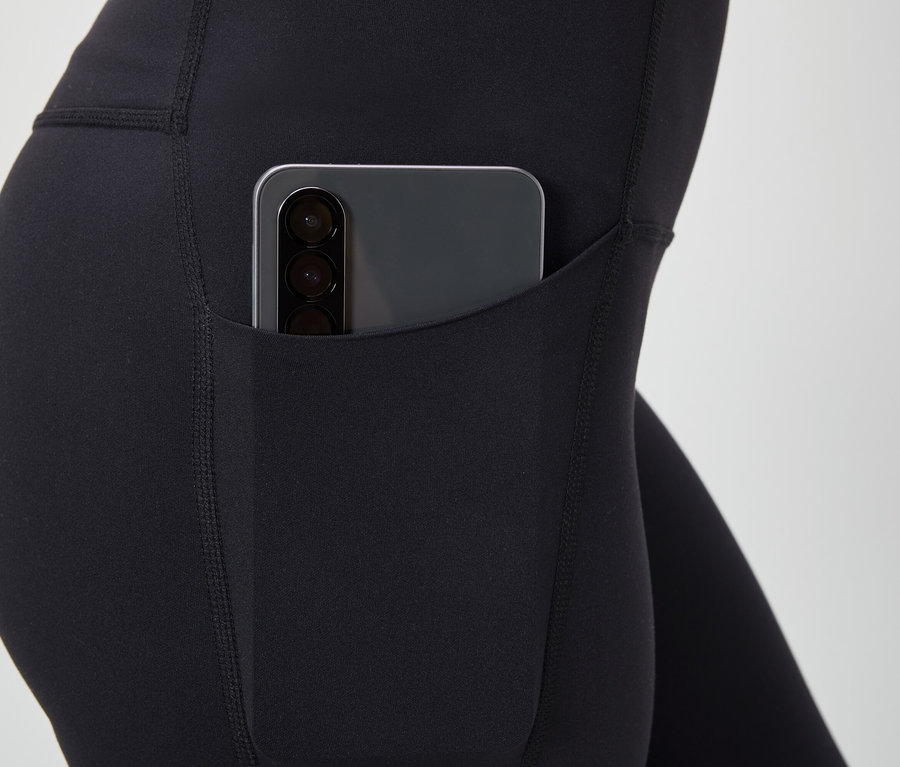 Detailansicht von schwarzen Leggings mit einem Smartphone in der Tasche.